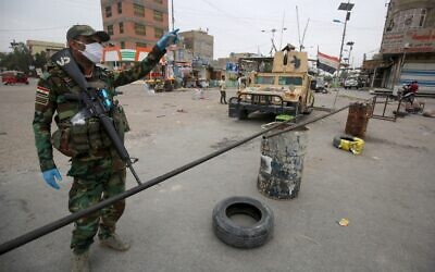 Illustrative: Iraqi soldiers, wearing protective face-masks and gloves, man a checkpoint at the entrance of Baghdad's eastern Sadr City suburb  as the country tries to stem the spread of the COVID-19, the disease caused by the novel coronavirus, March 28, 2020. (AHMAD AL-RUBAYE/AFP)