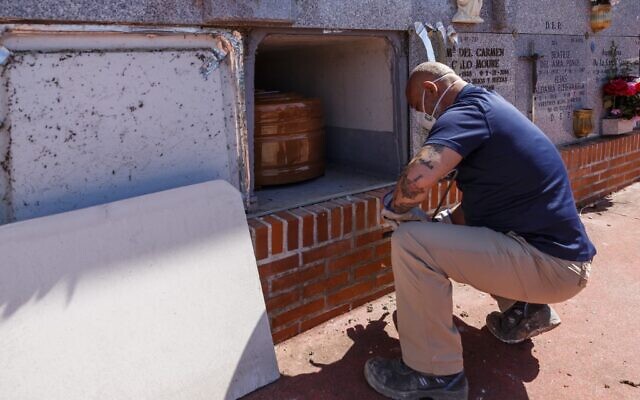 A mortuary employee wearing a face mask places the coffin of a COVID-19 coronavirus victim into a niche during a burial at the Fuencarral cemetery in Madrid on March 29, 2020. (BALDESCA SAMPER/AFP) A mortuary employee wearing a face mask places the coffin of a COVID-19 coronavirus victim into a niche during a burial at the Fuencarral cemetery in Madrid on March 29, 2020. (BALDESCA SAMPER/AFP)