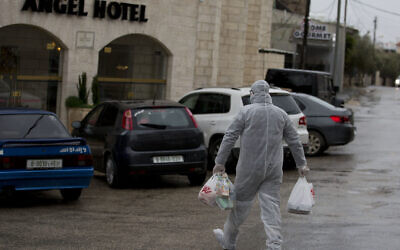 A Palestinian Authority policeman delivers supplies to the hotel staff which tested positive to coronavirus to a hotel in Bethlehem, West Bank, March 6, 2020. (AP Photo/Majdi Mohammed)