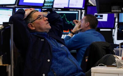 A pair of traders work in their booth on the floor of the New York Stock Exchange, Thursday, March 12, 2020. The deepening coronavirus crisis is sending stocks into another alarming slide on Wall Street, triggering a brief, automatic shutdown in trading for the second time this week. (AP Photo/Richard Drew)