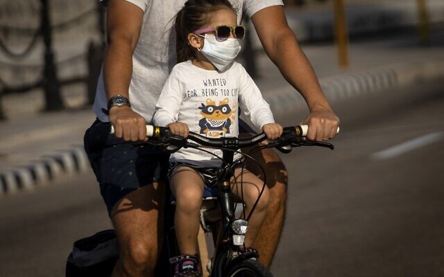 A girl wearing a protective face mask as a preventive measure against the spread of the new coronavirus ride a bicycle with her father in Havana, Cuba, Saturday, March 21, 2020. (AP Photo/Ramon Espinosa) A girl wearing a protective face mask as a preventive measure against the spread of the new coronavirus ride a bicycle with her father in Havana, Cuba, Saturday, March 21, 2020. (AP Photo/Ramon Espinosa)