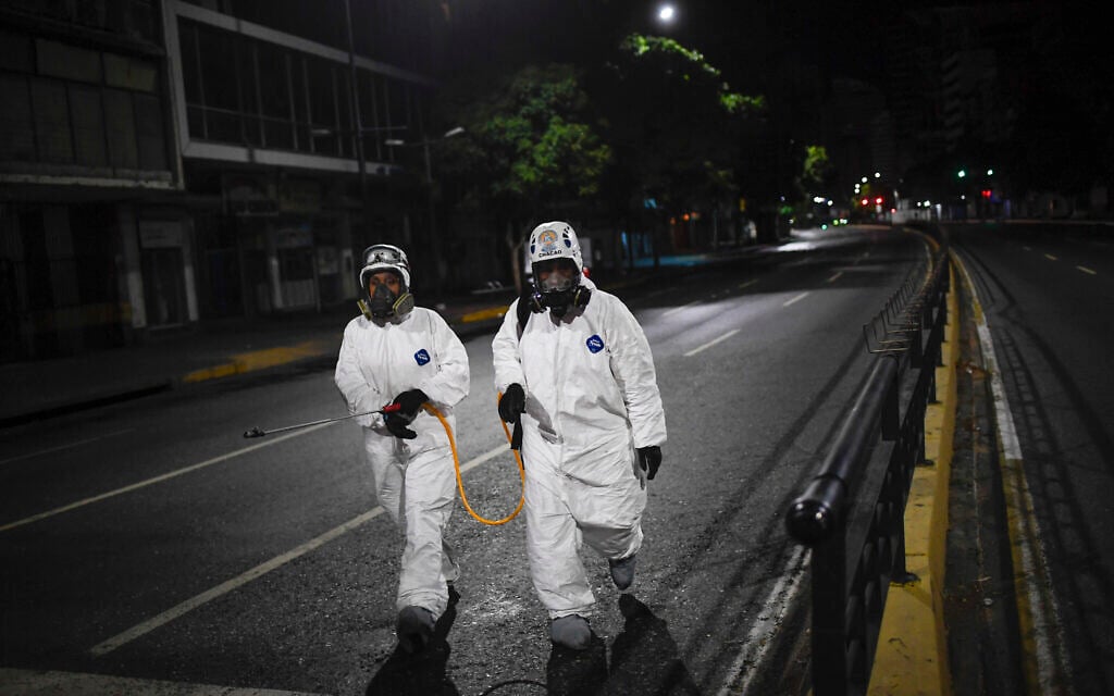 City workers walk after spraying disinfectant on the streets as a preventive measure against the spread of the new coronavirus, in Caracas, Venezuela, Saturday, March 21, 2020. (AP Photo/Matias Delacroix)