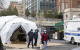 Medical Examiner personnel and construction workers are seen at the site of a makeshift morgue being built in New York, Wednesday, March 25, 2020.  (AP Photo/Mary Altaffer)