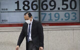 A man walks by an electronic stock board of a securities firm in Tokyo, March 30, 2020. (AP Photo/Koji Sasahara)