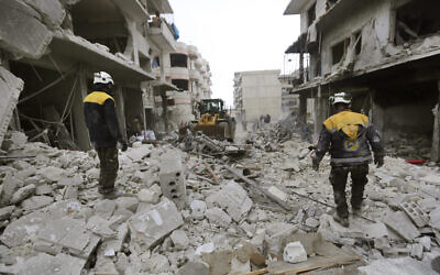 Syrian rescuers use a bulldozer to remove rubble of a destroyed building that covers a street after airstrikes in the town of Ariha, in Idlib province, Syria, January 30, 2020. (AP Photo/Ghaith Alsayed)