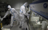 French lab scientists in hazmat gear inserting liquid in test tube manipulate potentially infected patient samples at Pasteur Institute in Paris, February 6, 2020. (Francois Mori/AP)