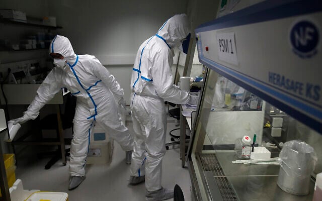French lab scientists in hazmat gear inserting liquid in test tube manipulate potentially infected patient samples at Pasteur Institute in Paris, February 6, 2020. (Francois Mori/AP) French lab scientists in hazmat gear inserting liquid in test tube manipulate potentially infected patient samples at Pasteur Institute in Paris, February 6, 2020. (Francois Mori/AP)