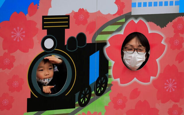 A man poses for photos with his son during a cherry blossom festival in Matsuda, Kanagawa prefecture, south of Tokyo, Saturday, Feb. 29, 2020. (AP/Jae C. Hong) A man poses for photos with his son during a cherry blossom festival in Matsuda, Kanagawa prefecture, south of Tokyo, Saturday, Feb. 29, 2020. (AP/Jae C. Hong)