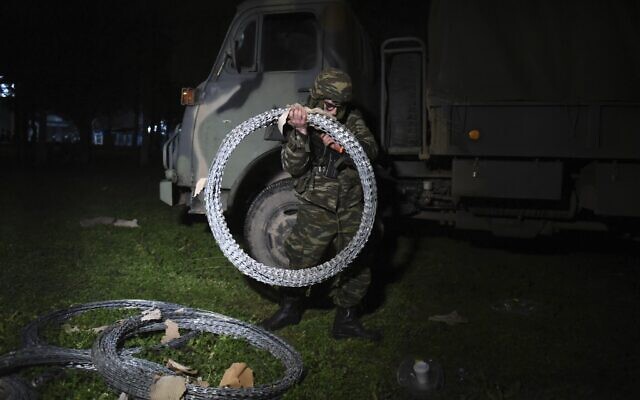 A Greek soldier carries a razor wire fencing at Kastanies border gate at the Greek-Turkish border, February 29, 2020. (Giannis Papanikos/AP)