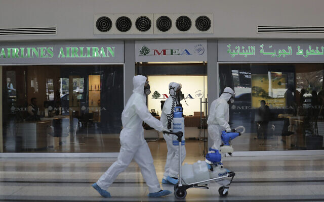 Workers wearing protective gear walk in front of the Middle East Airlines office as spray disinfectant as a precaution against the coronavirus outbreak, in the departure terminal at the Rafik Hariri International Airport, in Beirut, Lebanon, Thursday, March 5, 2020. (AP/Hassan Ammar) Workers wearing protective gear walk in front of the Middle East Airlines office as spray disinfectant as a precaution against the coronavirus outbreak, in the departure terminal at the Rafik Hariri International Airport, in Beirut, Lebanon, Thursday, March 5, 2020. (AP/Hassan Ammar)