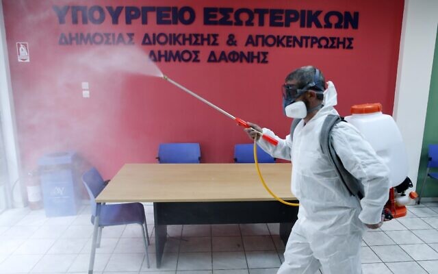 A worker wearing a protective suit sprays disinfectant inside a citizen's service office in the Athens' eastern suburb of Dafni, March 9, 2020. The sign reads "Interior Ministry. Municipality of Dafni." (Thanassis Stavrakis/AP) A worker wearing a protective suit sprays disinfectant inside a citizen's service office in the Athens' eastern suburb of Dafni, March 9, 2020. The sign reads "Interior Ministry. Municipality of Dafni." (Thanassis Stavrakis/AP)