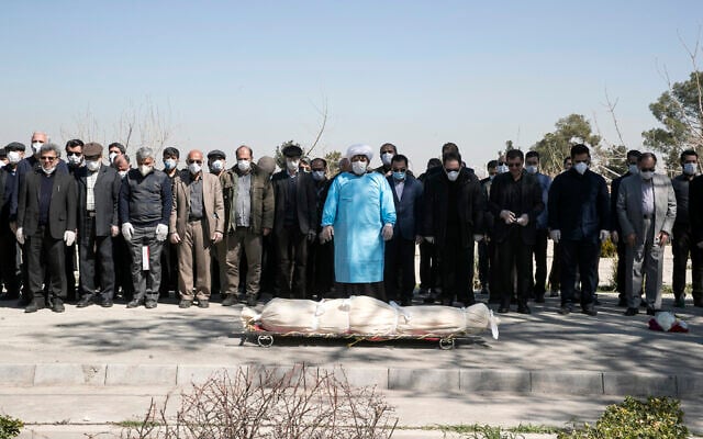 Mourners wearing face masks and gloves pray over the body of former politburo official in the Revolutionary Guard Farzad Tazari, who died Monday after being infected with the new coronavirus, at the Behesht-e-Zahra cemetery just outside Tehran, Iran, March 10, 2020 (Mahmood Hosseini/Tasnim News Agency via AP) Mourners wearing face masks and gloves pray over the body of former politburo official in the Revolutionary Guard Farzad Tazari, who died Monday after being infected with the new coronavirus, at the Behesht-e-Zahra cemetery just outside Tehran, Iran, March 10, 2020 (Mahmood Hosseini/Tasnim News Agency via AP)