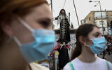 Illustrative: Girls wear face masks during celebrations of the Jewish festival of Purim in Bnei Brak, Israel, Tuesday, March 10, 2020.  (AP Photo/Oded Balilty)