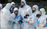 Workers from a Servpro disaster recovery team wearing protective suits and respirators are given supplies as they line up before entering the Life Care Center in Kirkland, Washington, to begin cleaning and disinfecting the facility, March 11, 2020. (AP Photo/Ted S. Warren)