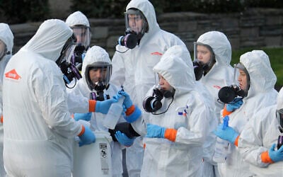Workers from a Servpro disaster recovery team wearing protective suits and respirators are given supplies as they line up before entering the Life Care Center in Kirkland, Washington, to begin cleaning and disinfecting the facility, March 11, 2020. (AP Photo/Ted S. Warren)