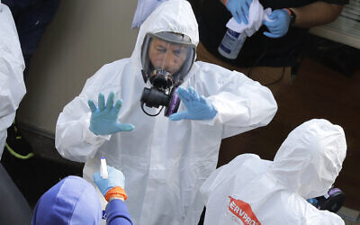 Servpro cleaning workers are sprayed as they exit the Life Care Center in Kirkland, Wash., Thursday, March 12, 2020, at the end of a day spent cleaning inside the facility near Seattle. The nursing home is at the center of the outbreak of the new coronavirus in Washington state. (AP Photo/Ted S. Warren)