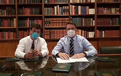 In this handout photo released by Brazil's Presidential Press Office, Brazilian Health Minister Luiz Henrique Mandetta, left, and President Jair Bolsonaro, wear masks as they speak about the new coronavirus during a Facebook Live transmission, in Brasilia, Brazil, Thursday, March 12, 2020.(Brazil's Presidential Press Office via AP)