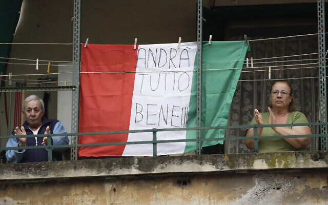 A couple applauds next to an Italian flag reading 'everything will be alright,' at the Garbatella neighborhood, in Rome, March 14, 2020 (AP Photo/Alessandra Tarantino) A couple applauds next to an Italian flag reading 'everything will be alright,' at the Garbatella neighborhood, in Rome, March 14, 2020 (AP Photo/Alessandra Tarantino)