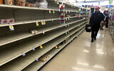 A shopper walks past empty shelves where bread is normally displayed in a supermarket, March 15, 2020, in Boston. (AP Photo/Steven Senne)