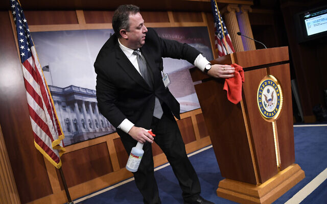 Mike Mastrian, director of the Senate Radio and Television Gallery, cleans down the podium before a news conference on Capitol Hill in Washington, March 17, 2020. (Susan Walsh/AP) Mike Mastrian, director of the Senate Radio and Television Gallery, cleans down the podium before a news conference on Capitol Hill in Washington, March 17, 2020. (Susan Walsh/AP)