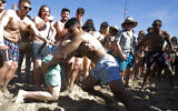 Two men wrestle each other as spring break revelers look on during a contest on the beach, March 17, 2020, in Pompano Beach, Florida (AP Photo/Julio Cortez)
