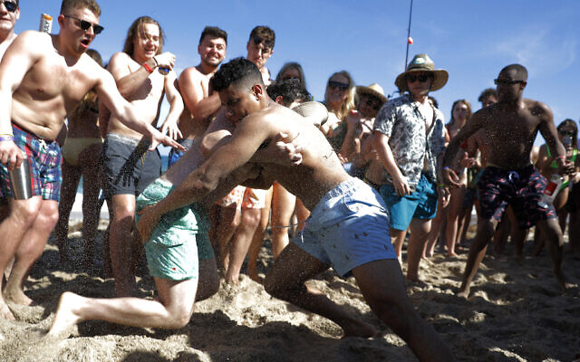 Two men wrestle each other as spring break revelers look on during a contest on the beach, March 17, 2020, in Pompano Beach, Florida (AP Photo/Julio Cortez) Two men wrestle each other as spring break revelers look on during a contest on the beach, March 17, 2020, in Pompano Beach, Florida (AP Photo/Julio Cortez)