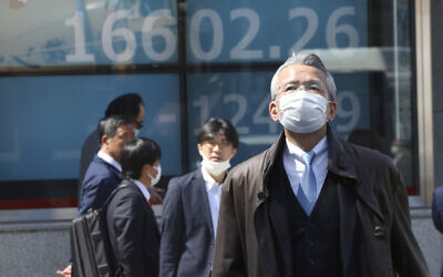 People walk by an electronic stock board of a securities firm in Tokyo, March 19, 2020 as shares in Asia failed to hold onto opening gains. (AP Photo/Koji Sasahara)