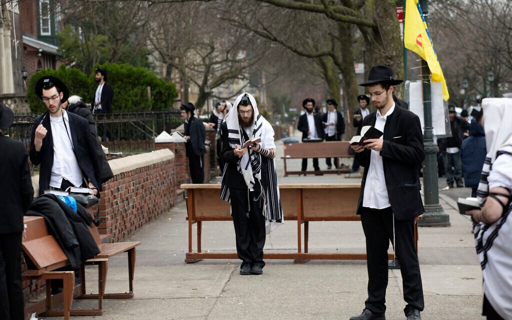 Orthodox Jewish men use 'social distancing' as they pray outside the Chabad Lubavitch World Headquarters, March 20, 2020, in the Brooklyn borough of New York, before leaders of six major organizations released a joint statement urging worshipers to 'avoid, to the maximum extent feasible, any outside interactions' to help stop the coronavirus pandemic. (AP Photo/Mark Lennihan)