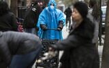 A woman dressed in a poncho, face mask and protective eyewear pushes her grocery cart in the Bedford-Stuyvesant neighborhood of Brooklyn, New York, on Friday, March 20, 2020. New York Gov. Andrew Cuomo is ordering all workers in non-essential businesses to stay home and banning gatherings statewide. Nonessential gatherings of individuals of any size or for any reason are canceled or postponed. (AP Photo/Wong Maye-E)