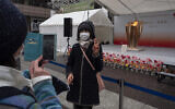 A woman poses for a photo with the Olympic Flame during a ceremony in Fukushima City, Japan, March 24, 2020 (AP Photo/Jae C. Hong)