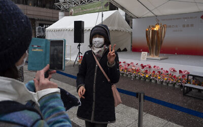 A woman poses for a photo with the Olympic Flame during a ceremony in Fukushima City, Japan, March 24, 2020 (AP Photo/Jae C. Hong)
