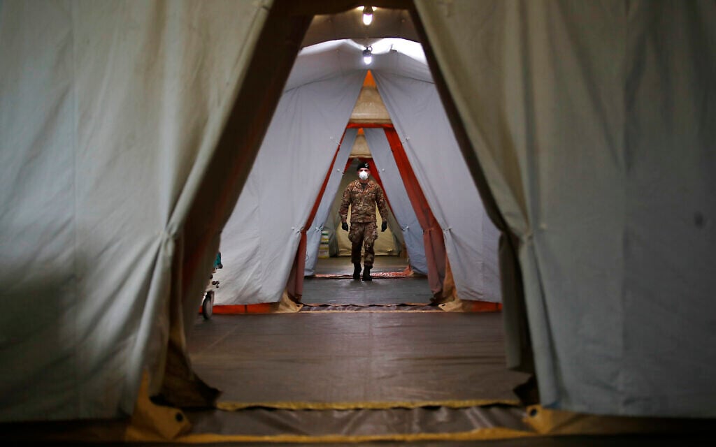 An Italian soldier walks inside the field hospital built in Crema, Italy, Tuesday, March 24, 2020. (AP Photo/Antonio Calanni)