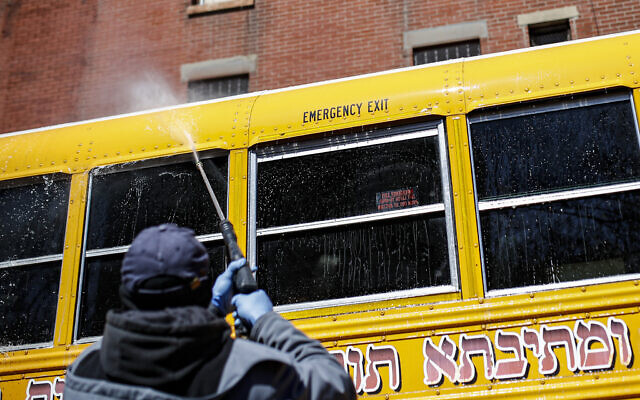 Illustrative: A worker covered in personal protective equipment power washes a school bus that serves an Ultra-Orthodox Jewish community in the Brooklyn borough of New York, March 27, 2020. (AP Photo/John Minchillo) Illustrative: A worker covered in personal protective equipment power washes a school bus that serves an Ultra-Orthodox Jewish community in the Brooklyn borough of New York, March 27, 2020. (AP Photo/John Minchillo)