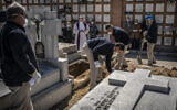 A priest and relatives pray as a victim of the COVID-19 is buried by undertakers at the Almudena cemetery in Madrid, Spain, March 28, 2020 (AP Photo/Olmo Calvo)