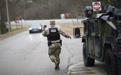 A member of the Rhode Island National Guard Military Police directs a motorist with New York license plates at a checkpoint on I-95 near the border with Connecticut where New Yorkers must pull over and provide contact information and are told to self-quarantine for two weeks, Saturday, March 28, 2020, in Hope Valley, R.I. (AP/David Goldman)