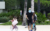 A man wears a mask as he walks along Waikiki Beach in Honolulu on Saturday, March 28, 2020. (AP/Caleb Jones)