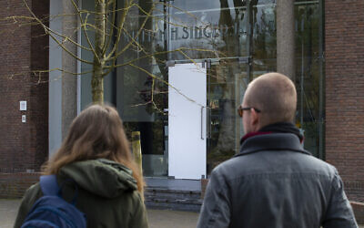 Two people look at the glass door which was smashed during a break-in at the Singer Museum in Laren, Netherlands, March 30, 2020 (AP Photo/Peter Dejong)