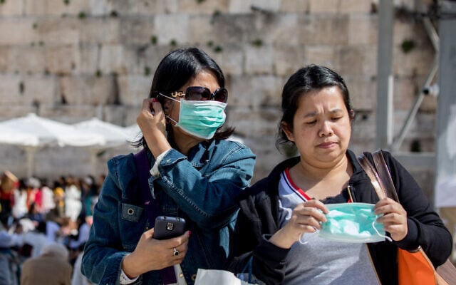 Tourists wearing face masks for fear of the coronavirus tours at the Western Wall in the Old City of Jerusalem on March 5, 2020. (Olivier Fitoussi/Flash90) Tourists wearing face masks for fear of the coronavirus tours at the Western Wall in the Old City of Jerusalem on March 5, 2020. (Olivier Fitoussi/Flash90)