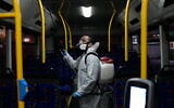 Workers wearing protective suits disinfect a bus as a preventive measure amid fears over the spread of the coronavirus, in Tel Aviv on March 9, 2020, . (Tomer Neuberg/Flash90)