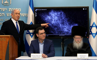 Prime Minister Benjamin Netanyahu with Health Minister Yaakov Litzman (right) and Health Ministry Director General Moshe Bar Siman-Tov at a press conference about the coronavirus COVID-19, at the Prime Minister's Office in Jerusalem on March 11, 2020. Netanyahu is explaining how the coronavirus can spread from a sneeze. (Flash90)