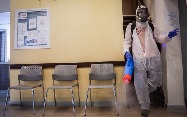 Workers wearing protective clothes disinfect a shop in Jerusalem, as a part of measues against spread of the novel coronavirus, on March 15, 2020. (Yonatan Sindel/Flash90) Workers wearing protective clothes disinfect a shop in Jerusalem, as a part of measues against spread of the novel coronavirus, on March 15, 2020. (Yonatan Sindel/Flash90)