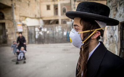 An ultra-Orthodox youth plays with a face mask in the neighborhood of Mea Sharim, Jerusalem, on March 16, 2020 (Yonatan Sindel/Flash90)