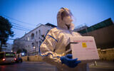 A Magen David Adom worker arrives to test a patient with symptoms of COVID-19, in Jerusalem on March 16, 2020. (Yonatan Sindel/Flash90)