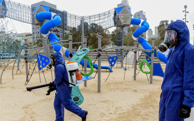 Workers wearing protective clothes disinfect a public playground in the coastal city of Bat Yam, on March 18, 2020 (Flash90) Workers wearing protective clothes disinfect a public playground in the coastal city of Bat Yam, on March 18, 2020 (Flash90)