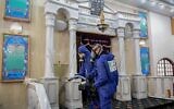 Workers wearing protective gear against the coronavirus disinfect a synagogue in Israel, March 18, 2020. (Flash90)