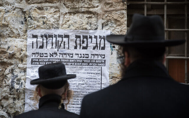 Ultra Orthodox Jewish men look at a "Pashkvil"- information poster about the Coronavirus in Jerusalem on March 18, 2020. (Yonatan Sindel/Flash90 ) Ultra Orthodox Jewish men look at a "Pashkvil"- information poster about the Coronavirus in Jerusalem on March 18, 2020. (Yonatan Sindel/Flash90 )