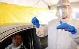 Magen David Adom staff wear protective clothing at a drive-through site to collect samples for coronavirus testing in Tel Aviv, March 20, 2020. (Tomer Neuberg/Flash90)