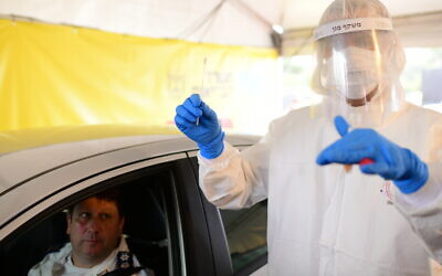 Magen David Adom staff wear protective clothing at a drive-through site to collect samples for coronavirus testing in Tel Aviv, March 20, 2020. (Tomer Neuberg/Flash90)
