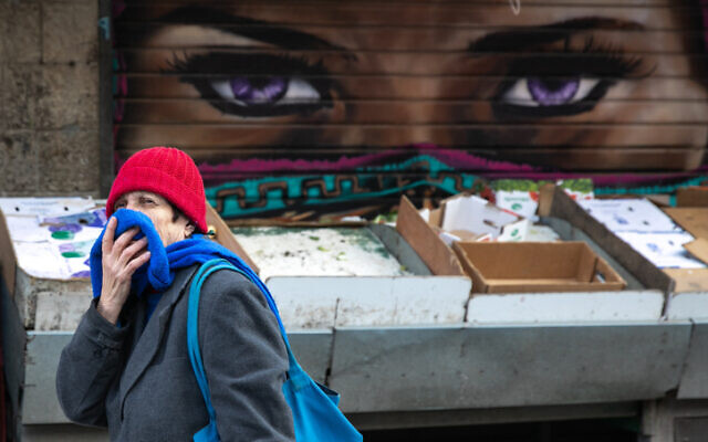 An Israeli woman, covering her nose and mouth for fear of the coronavirus, at the Mahane Yehuda Market in Jerusalem on March 22, 2020. (Olivier Fitoussi/Flash90)