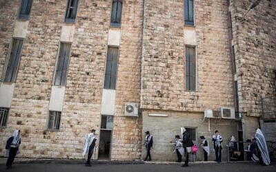 Men pray outside a synagogue in Bayit Vegan, Jerusalem, on March 22, 2020 (Yonatan Sindel/Flash 90)